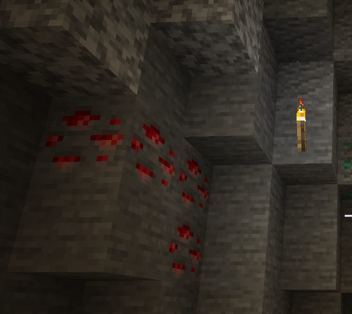A vein of redstone ore embedded in a stone cave wall in Minecraft, illuminated by a nearby torch.